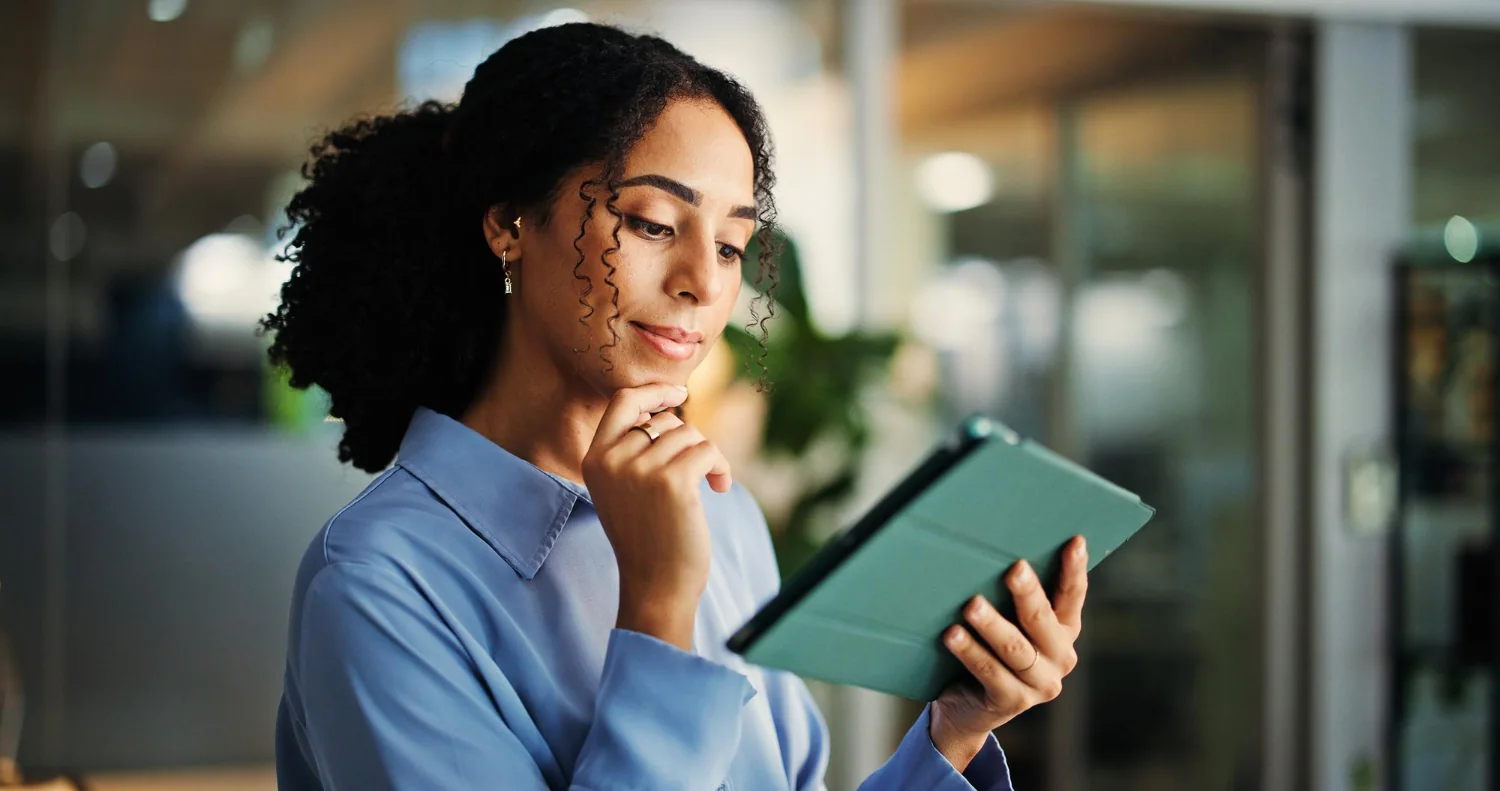 Como Consultar Protesto de Empresa pelo CNPJ: mulher consultando um tablet em um ambiente de trabalho